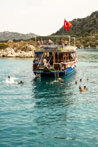 Tourists swim around a boat with a Turkish flag in the beautiful Mediterranean Sea.